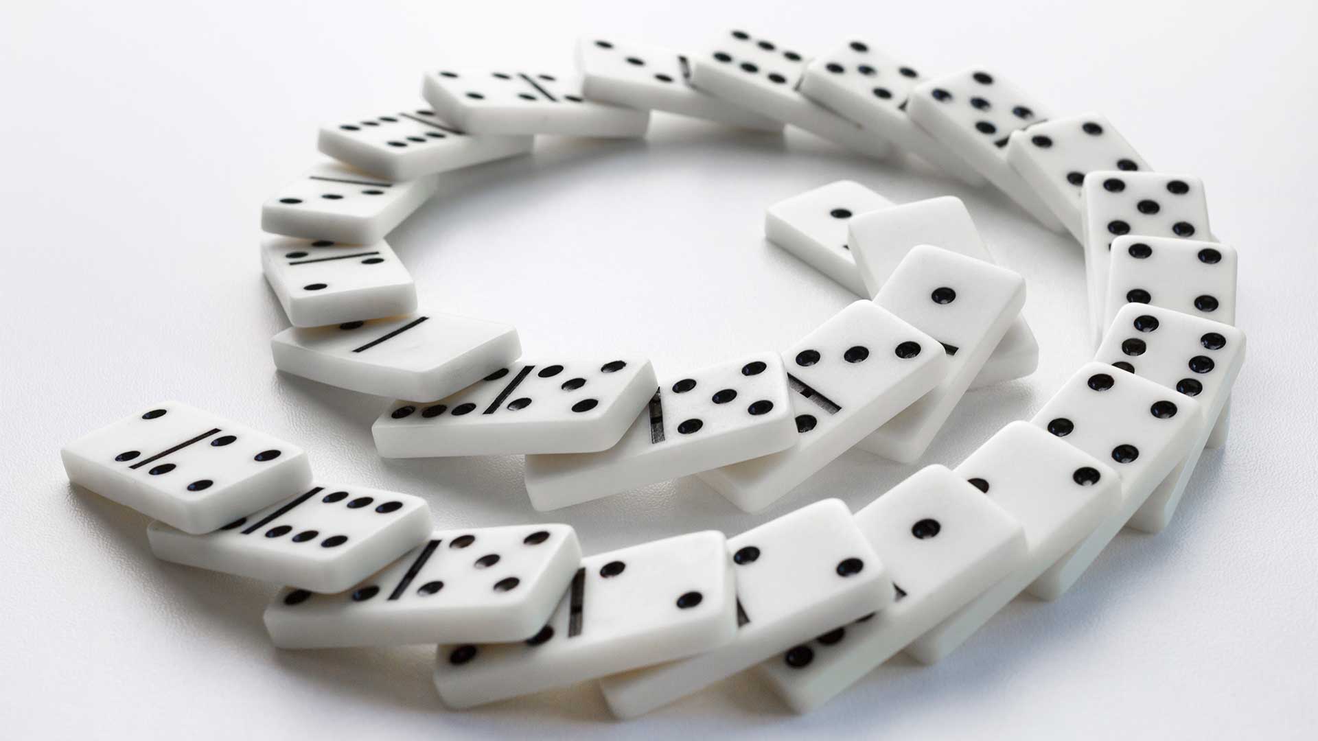 Falling dominoes in a spiral arrangement on a white background.