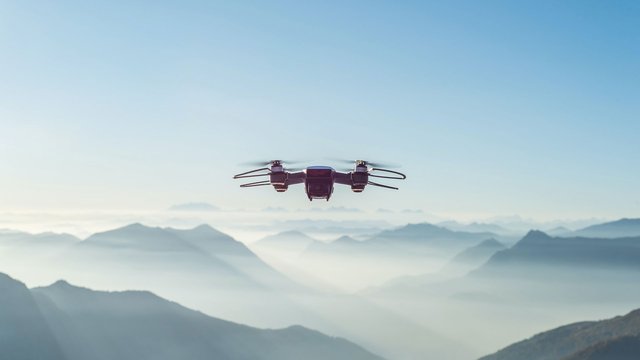 Drone flies over a misty mountain landscape under a clear sky.