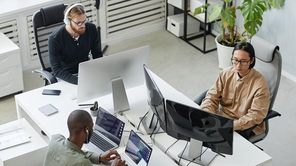 abat employees concentrate on their work at the computer in a modern office with plants.