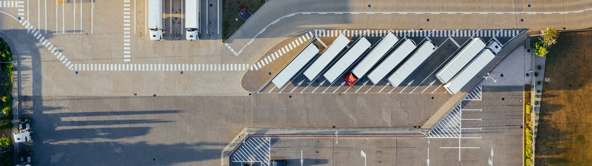 Aerial view of a logistics center with parked trucks at loading ramps and marked access routes.