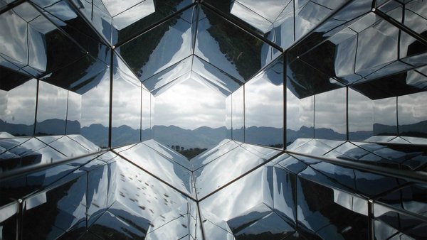 Geometric, mirrored panels reflect a mountain landscape and create an illusion of depth.