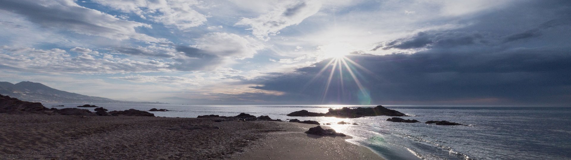 Sunset by the sea with dramatic sky and reflecting light on the water.