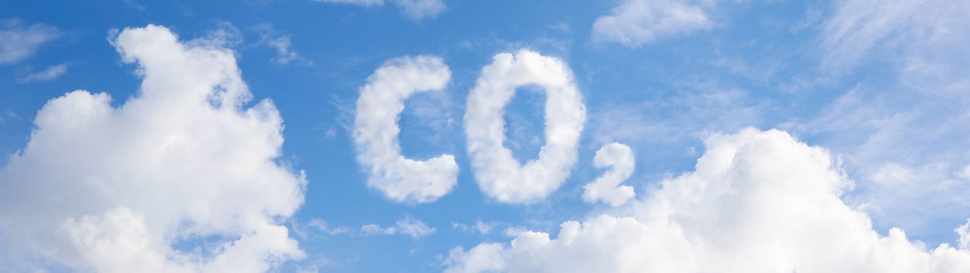 CO₂ lettering formed from white clouds in blue sky symbolizing greenhouse gases.