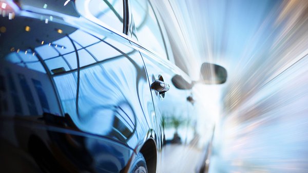 Close-up of a shiny car with a reflective surface showing speed through light effects.