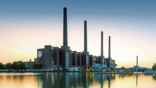 Volkswagen industrial building with four chimneys at sunset, reflection in the water.