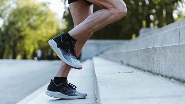 Athlete running up a flight of stairs, focus on running shoes and leg movement.