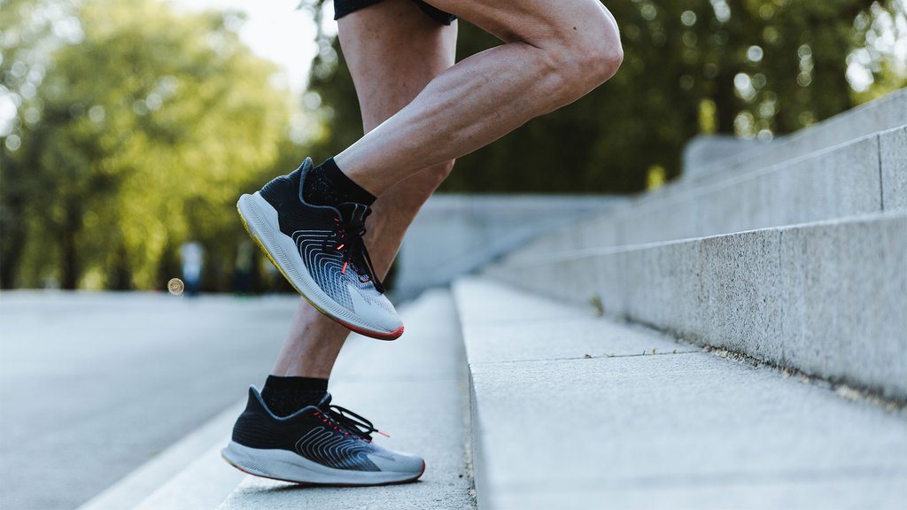 Athlete running up a flight of stairs, focus on running shoes and leg movement.
