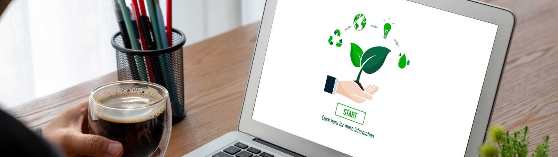 Person at a laptop with a sustainability graphic and a cup of coffee in hand.