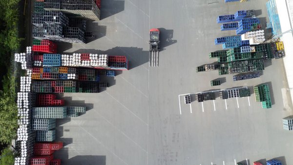 Aerial view of a storage area with stacked pallets and a forklift truck in motion.
