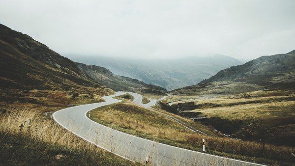 Winding country road through a hilly landscape with a misty atmosphere in the mountains.