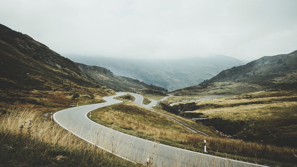 Winding country road through a hilly landscape with a misty atmosphere in the mountains.